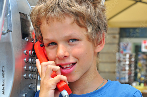 Smiling boy talking by public phone photo