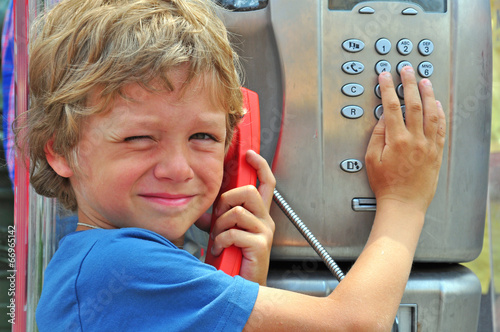 Small child talking by public phone photo