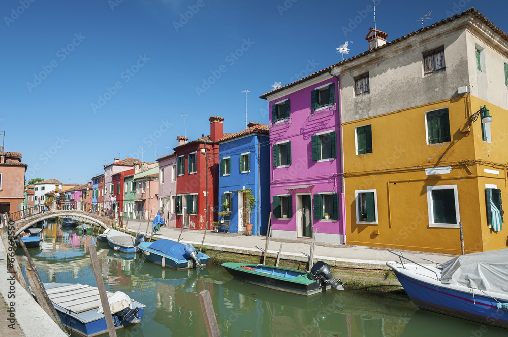 Burano island canal, colorful houses and boats, Italy.