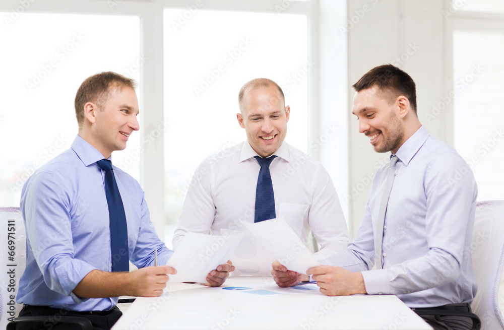 smiling businessmen with papers in office
