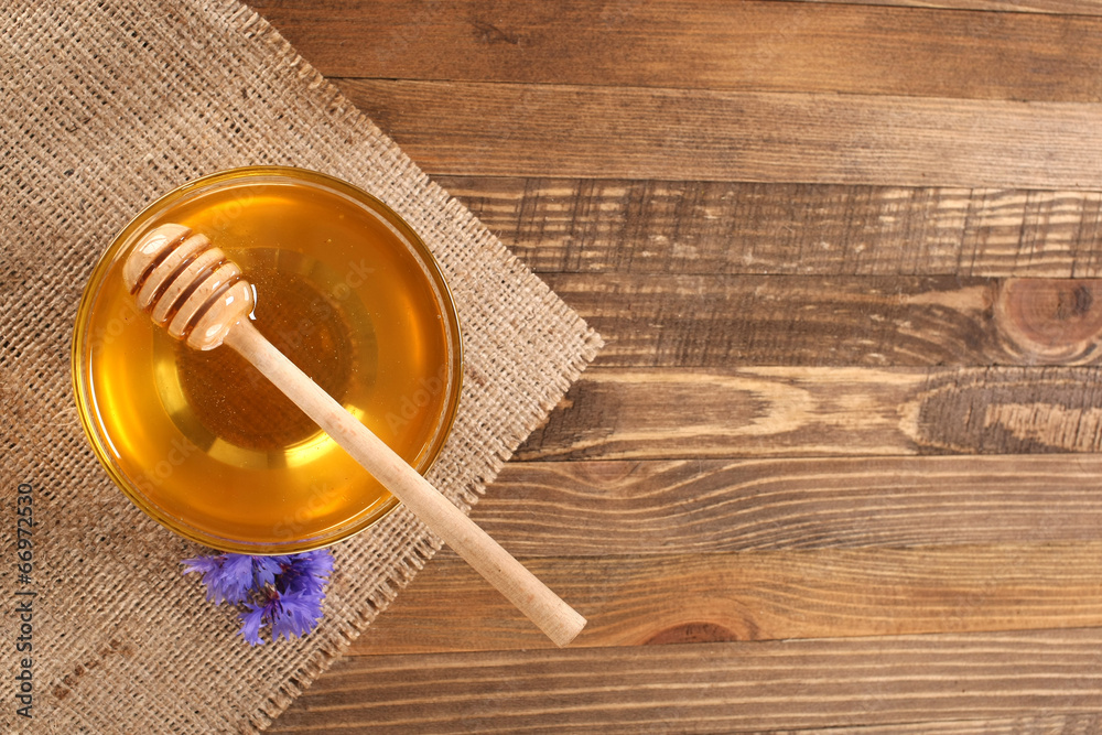 honey in a glass bowl on a wooden boards background honey in a glass bowl on a wooden boards background