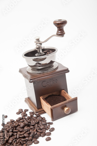 Isolated vintage coffee bean grinder and fresh ground coffee