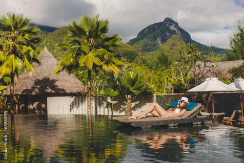 Beautiful young woman lying on a lounger next to the pool.