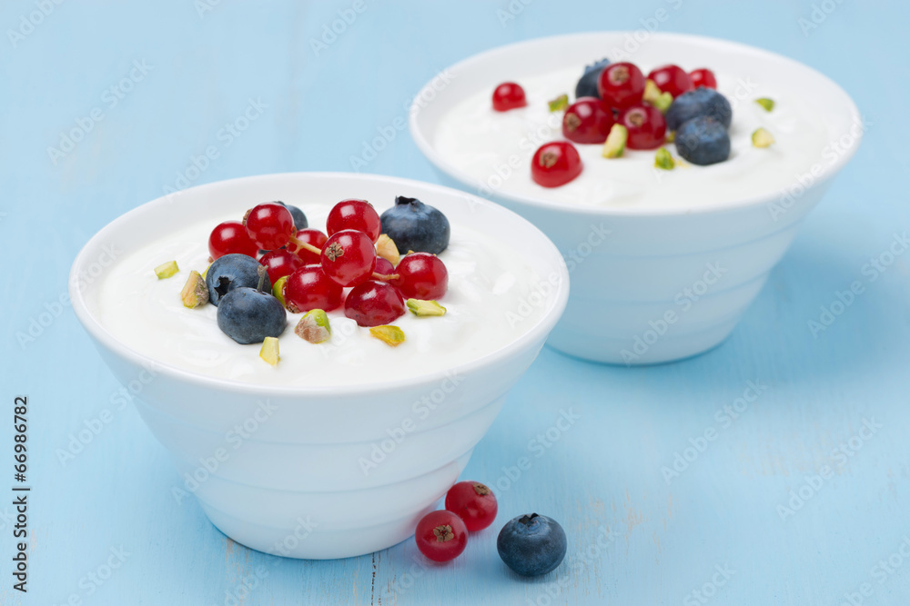 two bowls of fresh sweet yogurt with berries and pistachios two bowls of fresh sweet yogurt with berries and pistachios