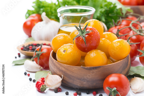 yellow and red cherry tomatoes in wooden bowl, olive oil, herbs