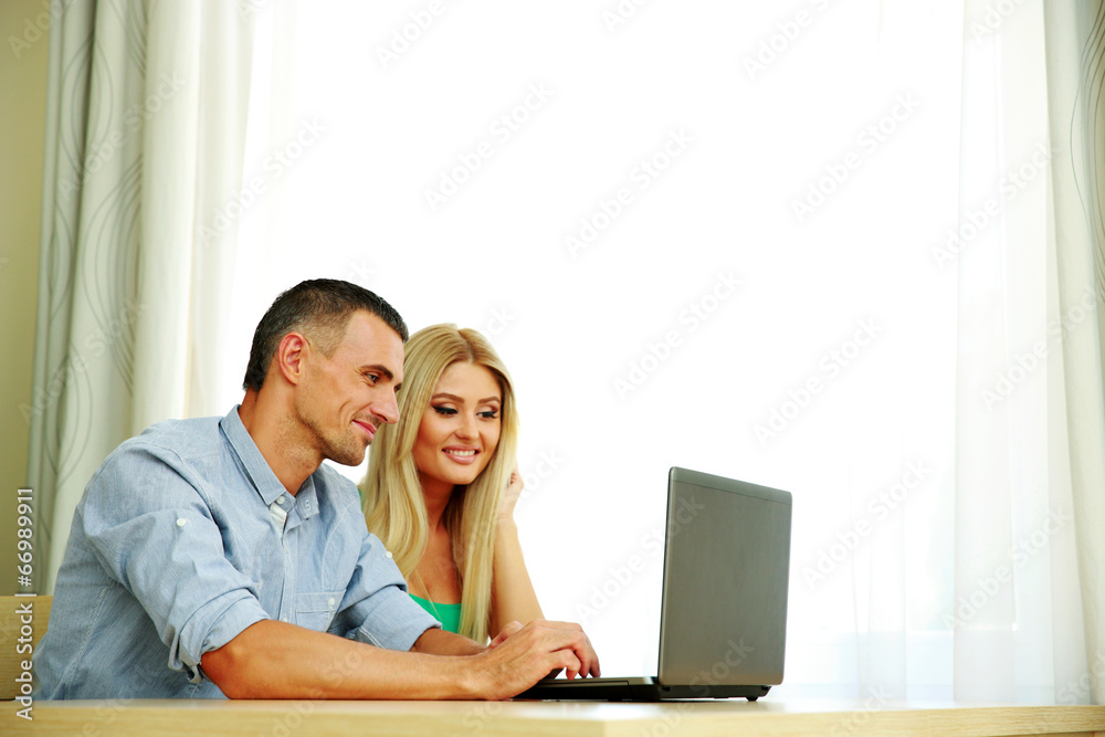 Happy couple using laptop together at home Happy couple using laptop together at home