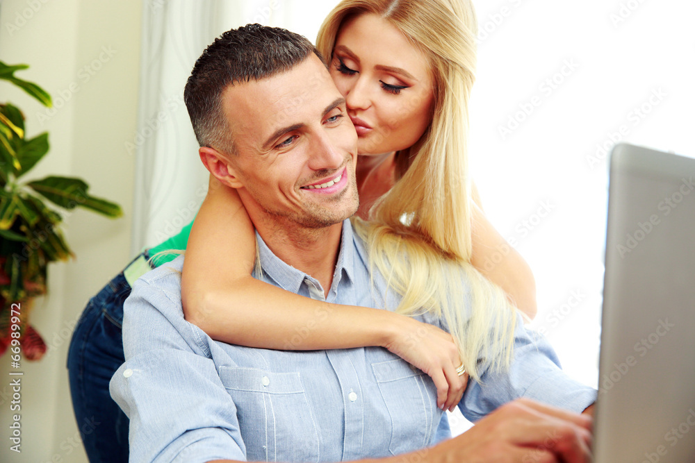 Portrait of a girl kissing her boyfriend while he using laptop Portrait of a girl kissing her boyfriend while he using laptop