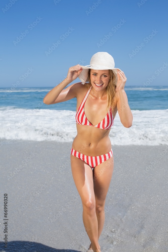Gorgeous fit woman in striped bikini and sunhat at beach Gorgeous fit woman in striped bikini and sunhat at beach
