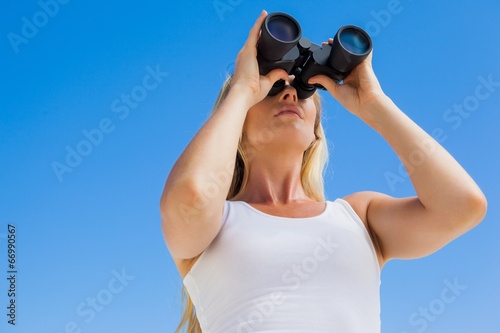 Blonde looking through binoculars on the beach © WavebreakmediaMicro
