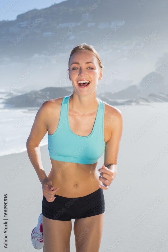 Fit woman smiling and jogging on the beach Fit woman smiling and jogging on the beach