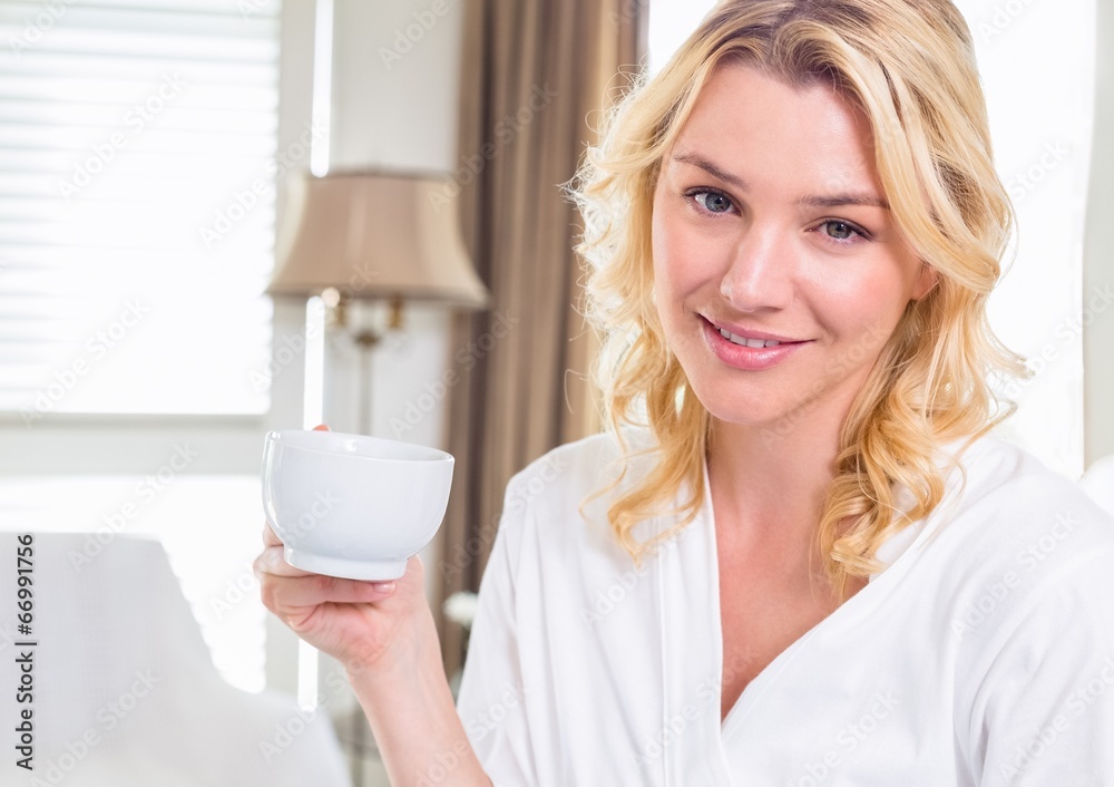 Pretty blonde in bathrobe drinking coffee smiling at camera Pretty blonde in bathrobe drinking coffee smiling at camera