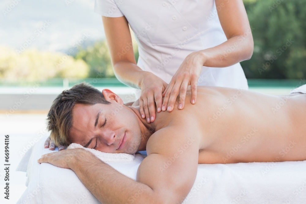 Handsome man getting a massage poolside Handsome man getting a massage poolside