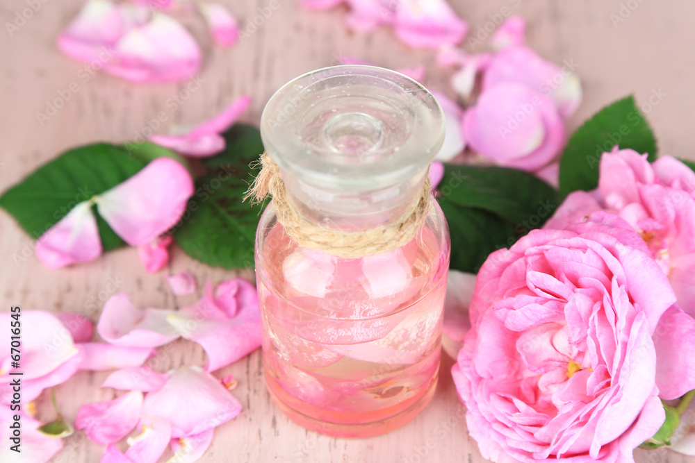 Rose oil in bottle on color wooden background Rose oil in bottle on color wooden background