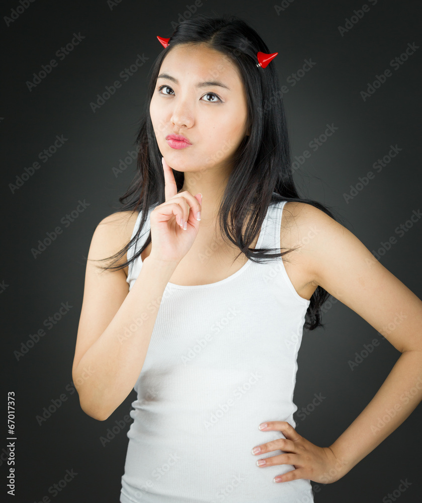 Asian young woman in devil horns and thinking with finger on Asian young woman in devil horns and thinking with finger on