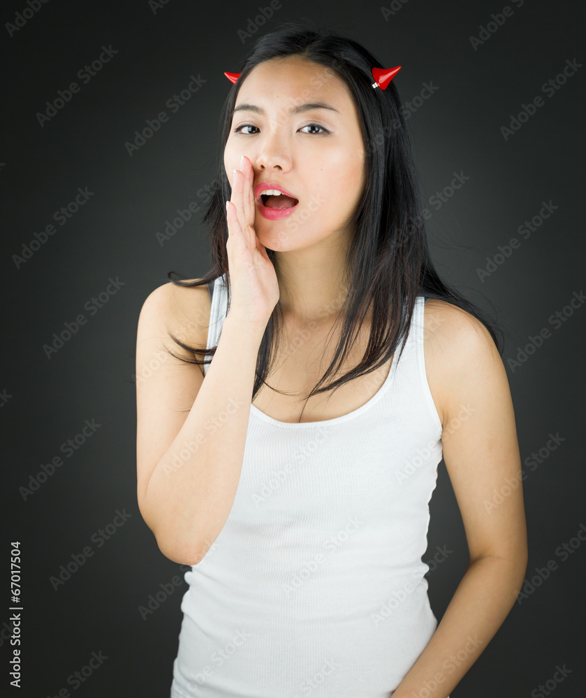 Asian young woman in devil horns whispering Asian young woman in devil horns whispering
