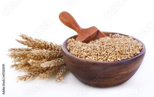 Ripe wheat in a wooden bowl on white background