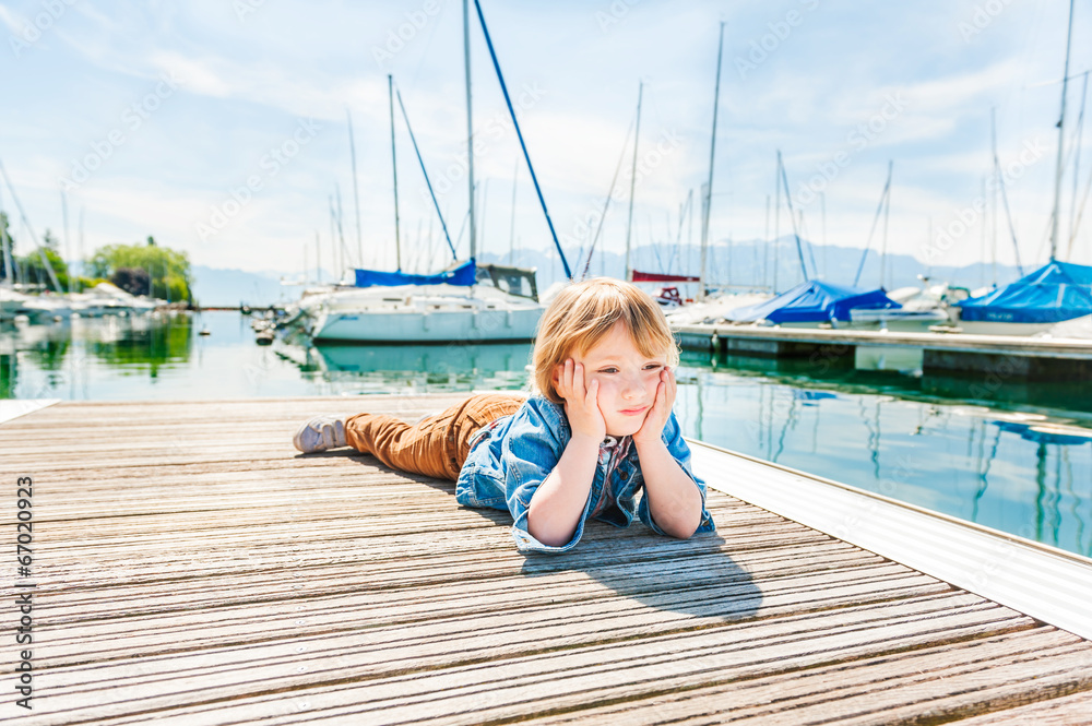 Sad toddler boy laying on a pier