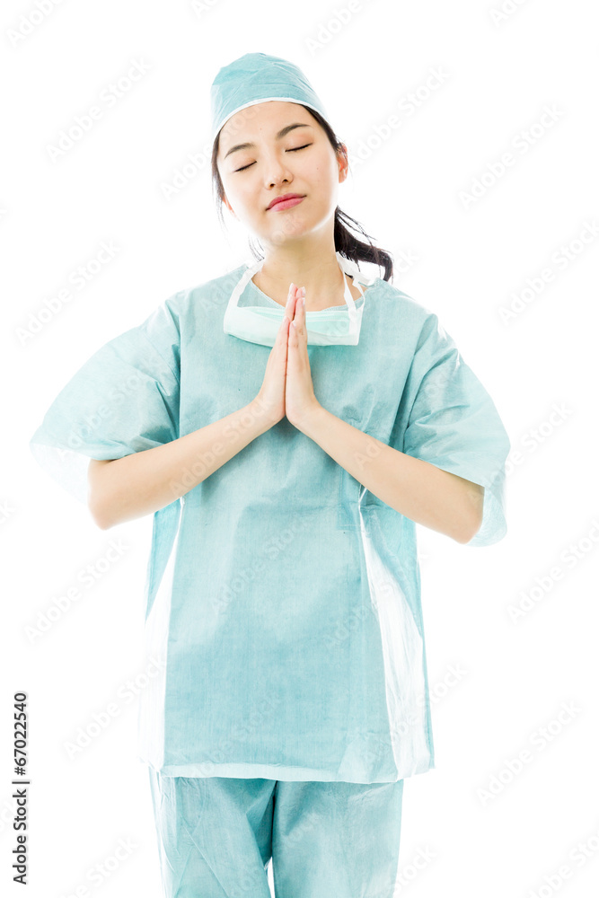 Asian female surgeon praying with hands clasped Asian female surgeon praying with hands clasped
