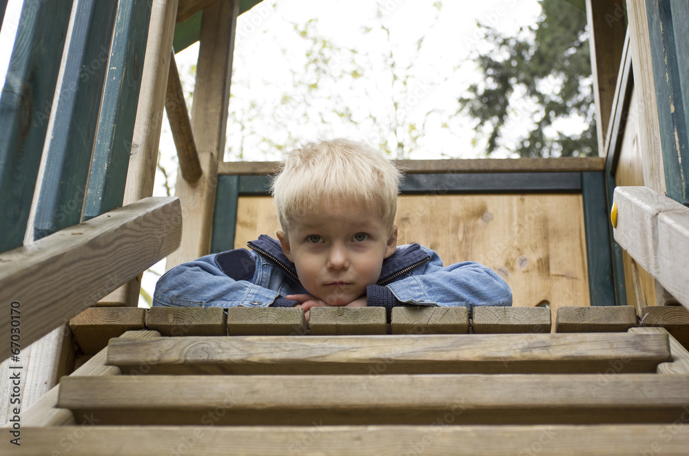 Small boy lying on his belly on top of the wooden stairs. Small boy lying on his belly on top of the wooden stairs.