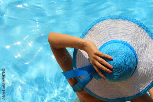 Young lady with white blue hat by the poolside