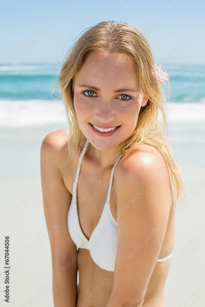 Beautiful blonde in white bikini smiling at camera on the beach Beautiful blonde in white bikini smiling at camera on the beach