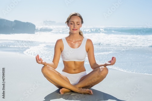 Gorgeous blonde in lotus pose by the sea