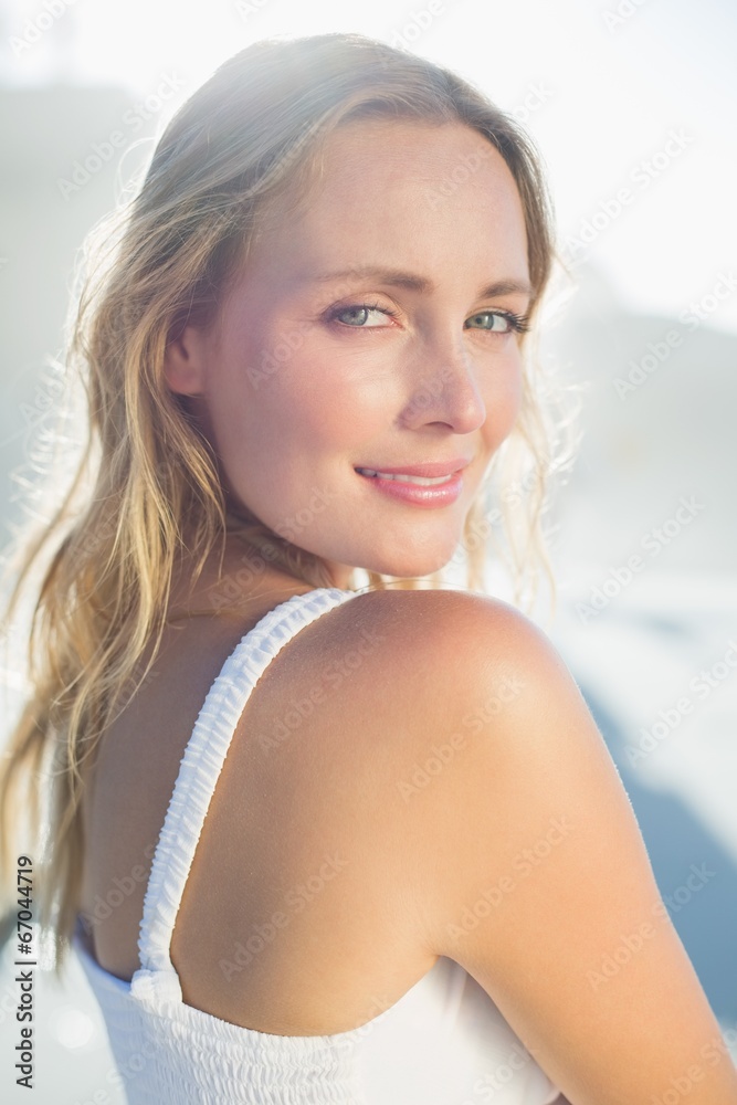 Pretty blonde standing at the beach in white sundress
