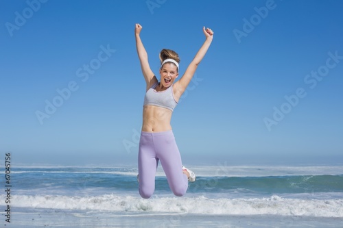 Sporty happy blonde jumping on the beach