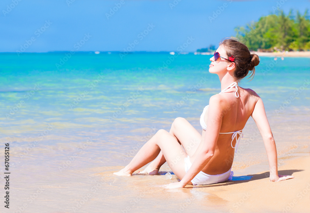 young woman in bikini sitting on tropical beach