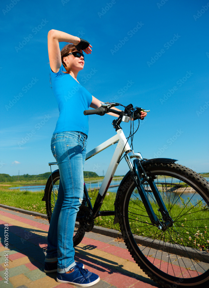 Young woman is standing in front of her bicycle Young woman is standing in front of her bicycle