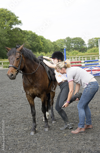 Young female rider gets help to mount her pony
