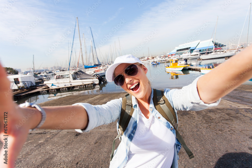 cheerful tourist taking selfie by wharf