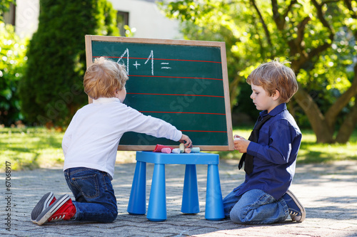 Two siblinig boys at blackboard practicing mathematics photo