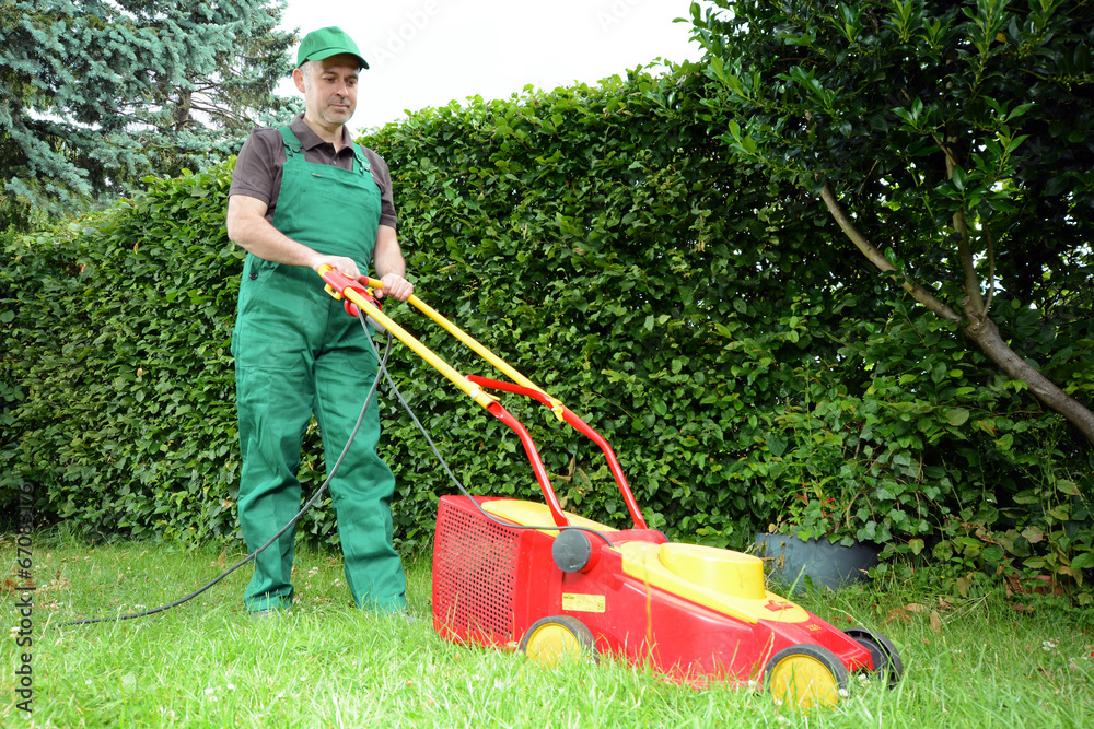 Gärtner mäht Wiese mit Rasenmäher Stock-Foto | Adobe Stock