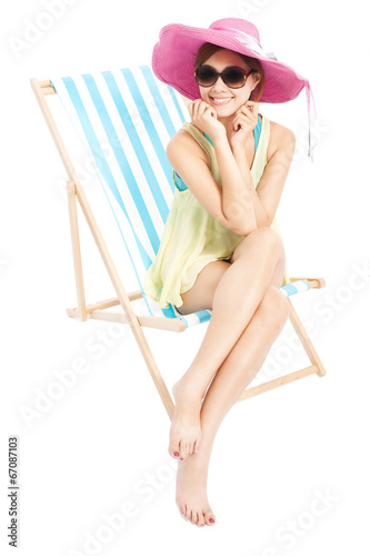 young fashion woman smiling and sitting on a beach chair