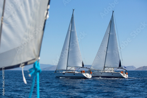Sailing ship yachts with white sails in a row.