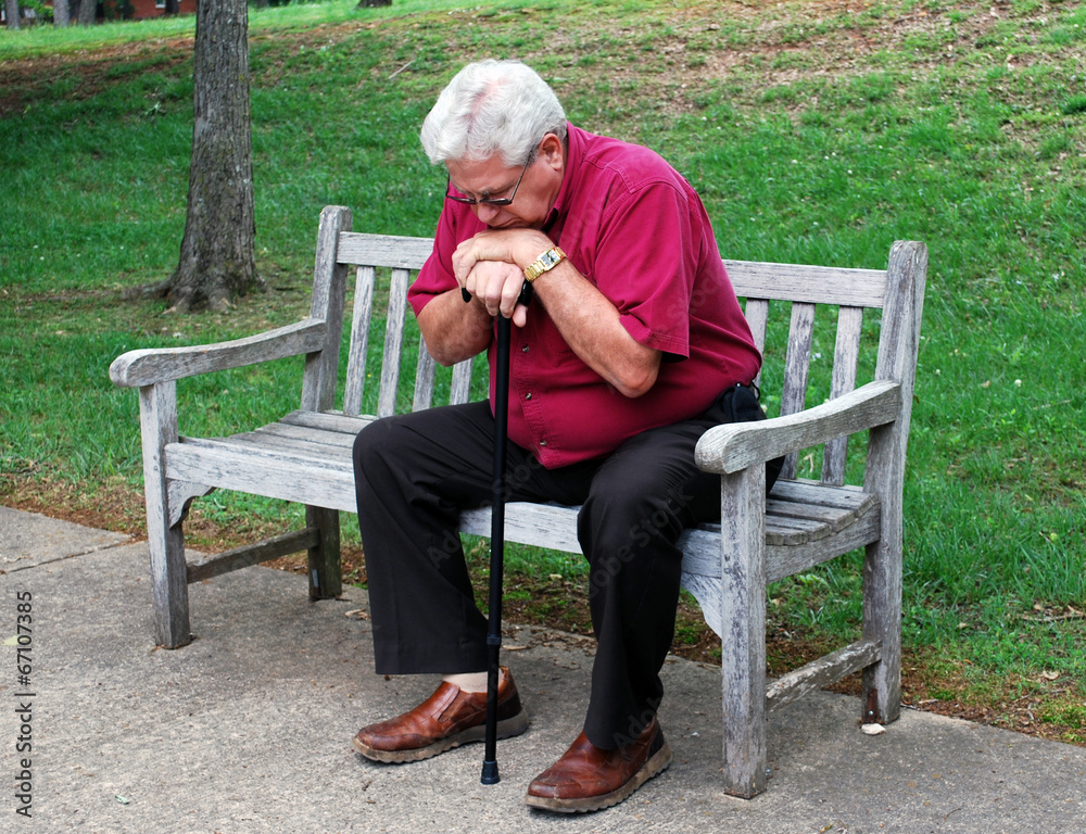 Fototapeta premium Elderly Man With Cane Sitting on a Park Bench