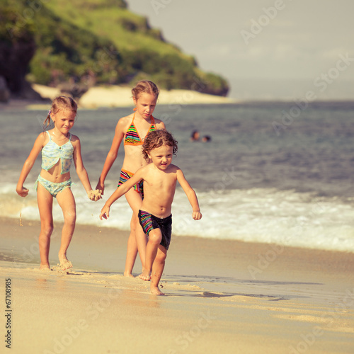 three little kids running on the beach