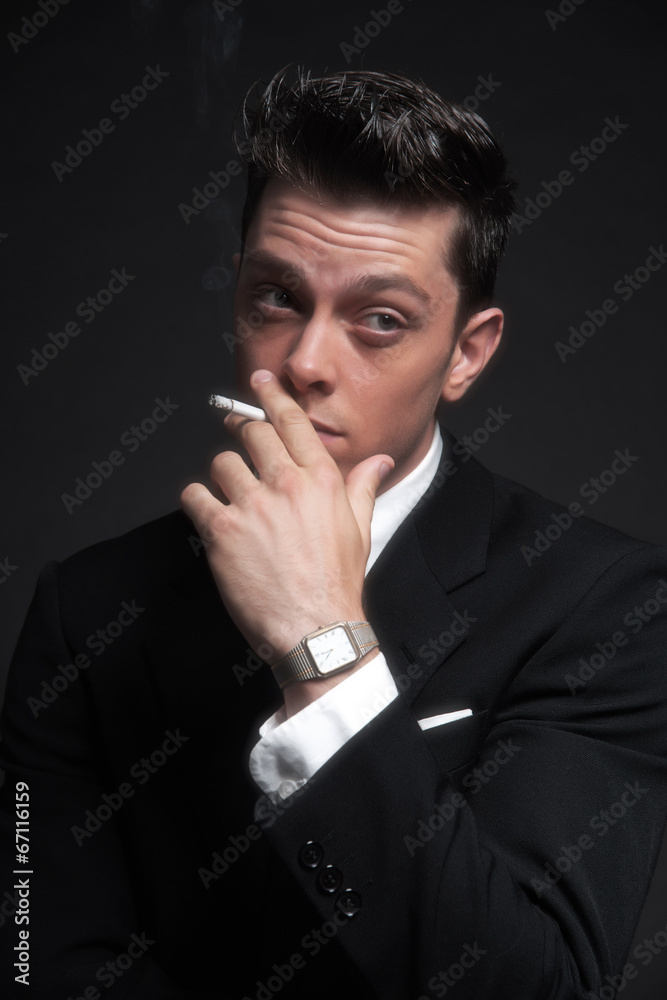Retro fifties fashion man smoking a cigarette. Wearing black sui Retro fifties fashion man smoking a cigarette. Wearing black sui