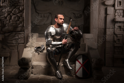Medieval knight sitting on the steps of ancient temple