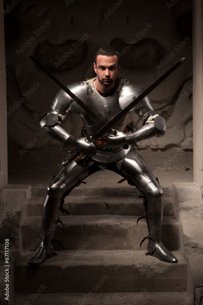 Medieval warrior posing on steps of ancient temple Medieval warrior posing on steps of ancient temple