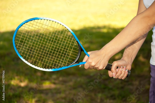 female hands holding a tennis racquet