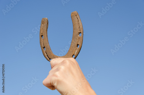 hand hold horseshoe symbol of luck on blue sky