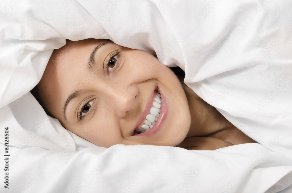 Happy woman hiding under the duvet Happy woman hiding under the duvet