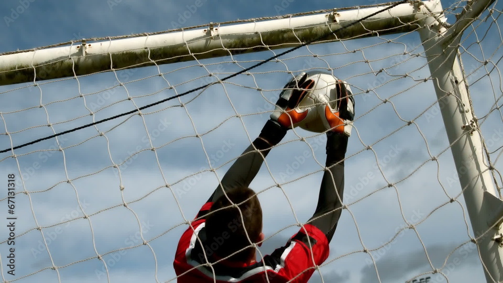 Goalkeeper in red saving a goal during a game