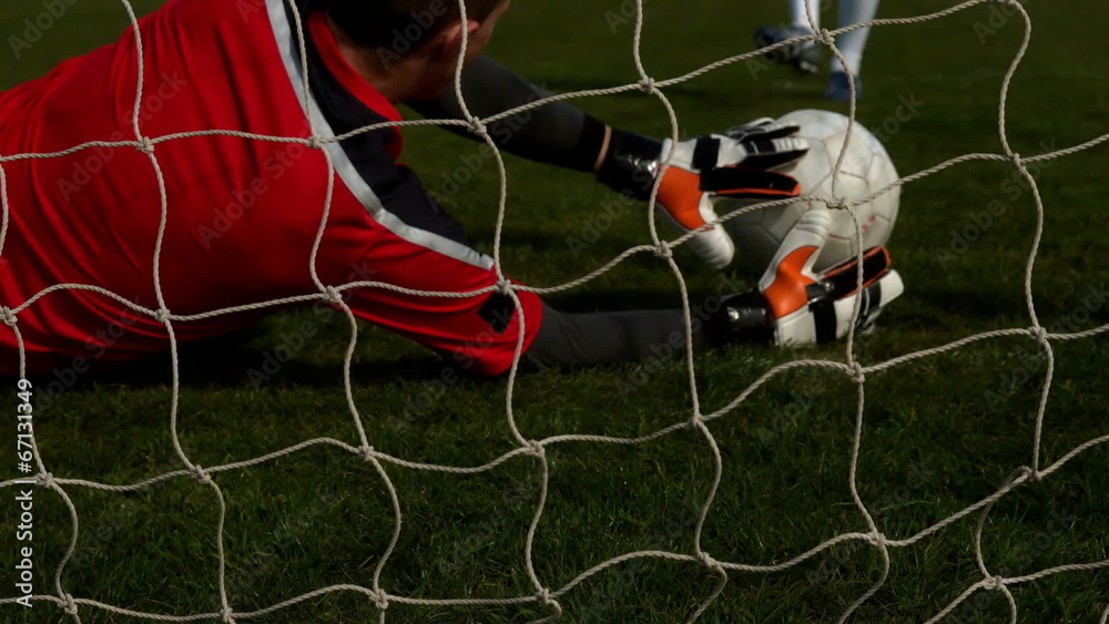 Goalkeeper in red letting in a goal during a game