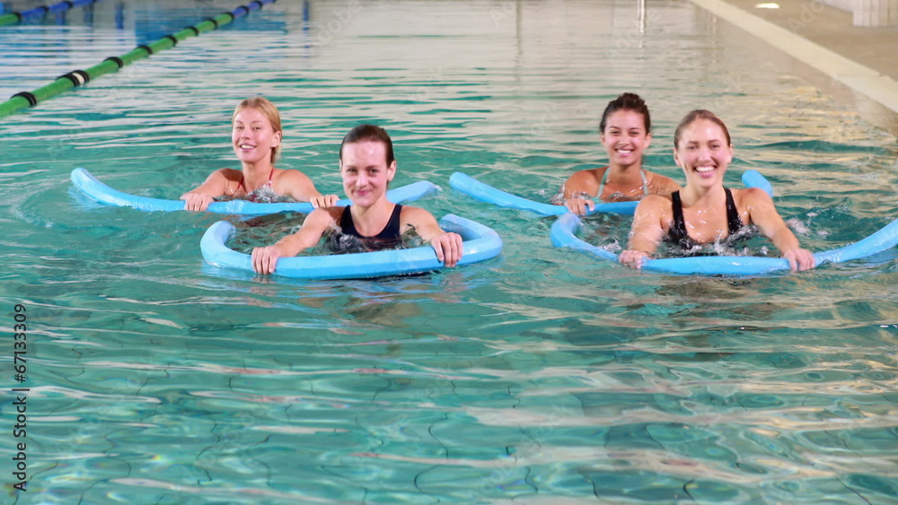 Four women doing aqua aerobics smiling at camera Four women doing aqua aerobics smiling at camera