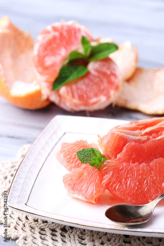 Ripe peeled grapefruits on plate, on color wooden background Ripe peeled grapefruits on plate, on color wooden background