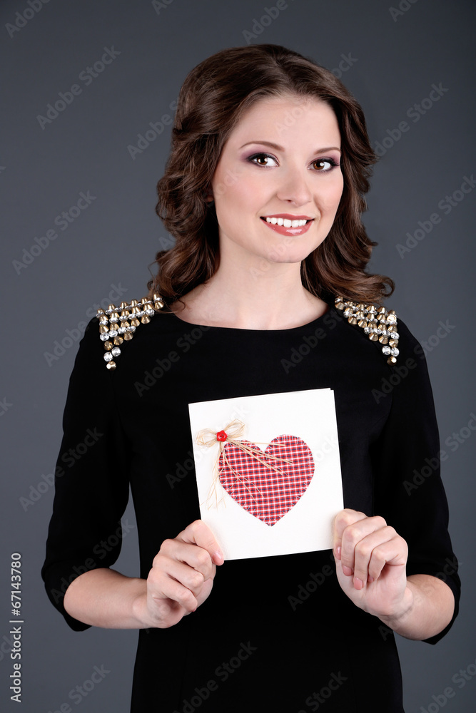 Beautiful young girl in dress with card on grey background Beautiful young girl in dress with card on grey background