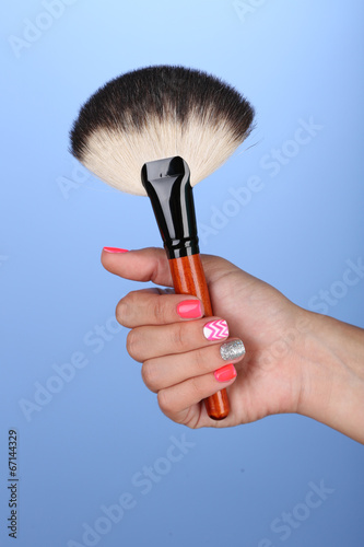 Female hand with stylish colorful nails holding brush,
